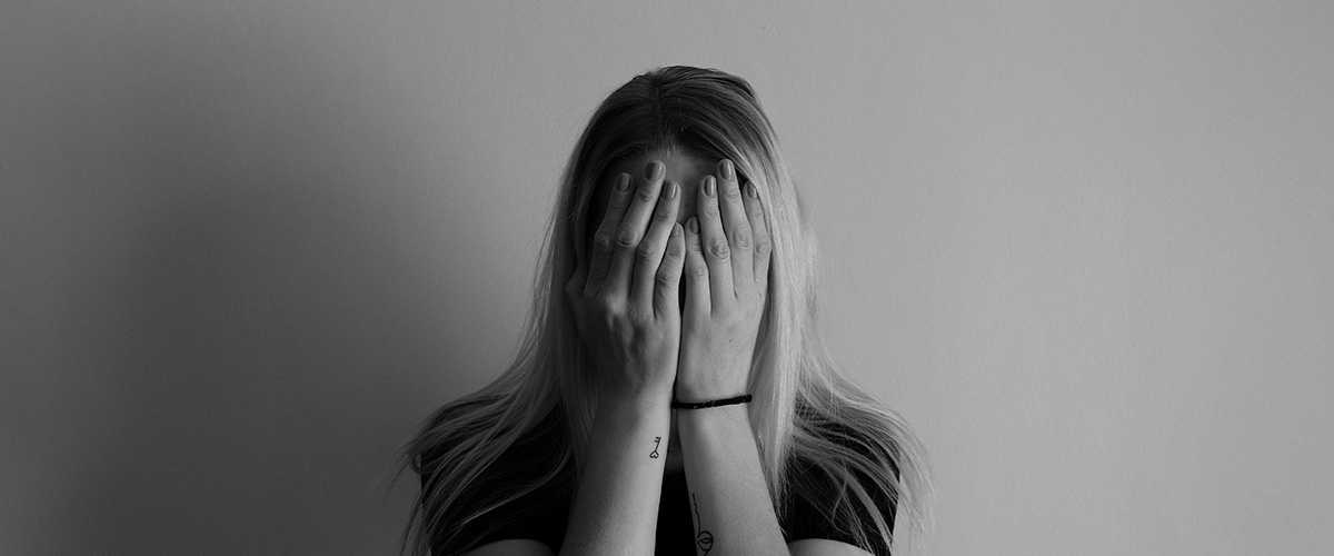 black and white photo of woman standing with her hands covering over her face