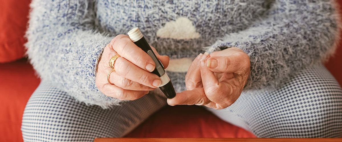 A woman is pricking her finger to take a blood glucose reading