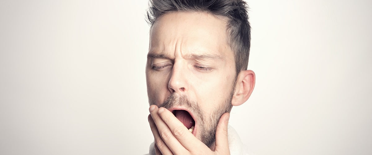 man yawning, hand over mouth