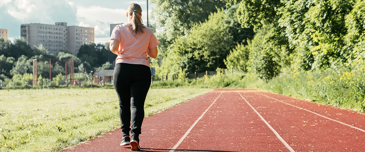 women in t-shirt and leggings walking on a exercise track outdoors
