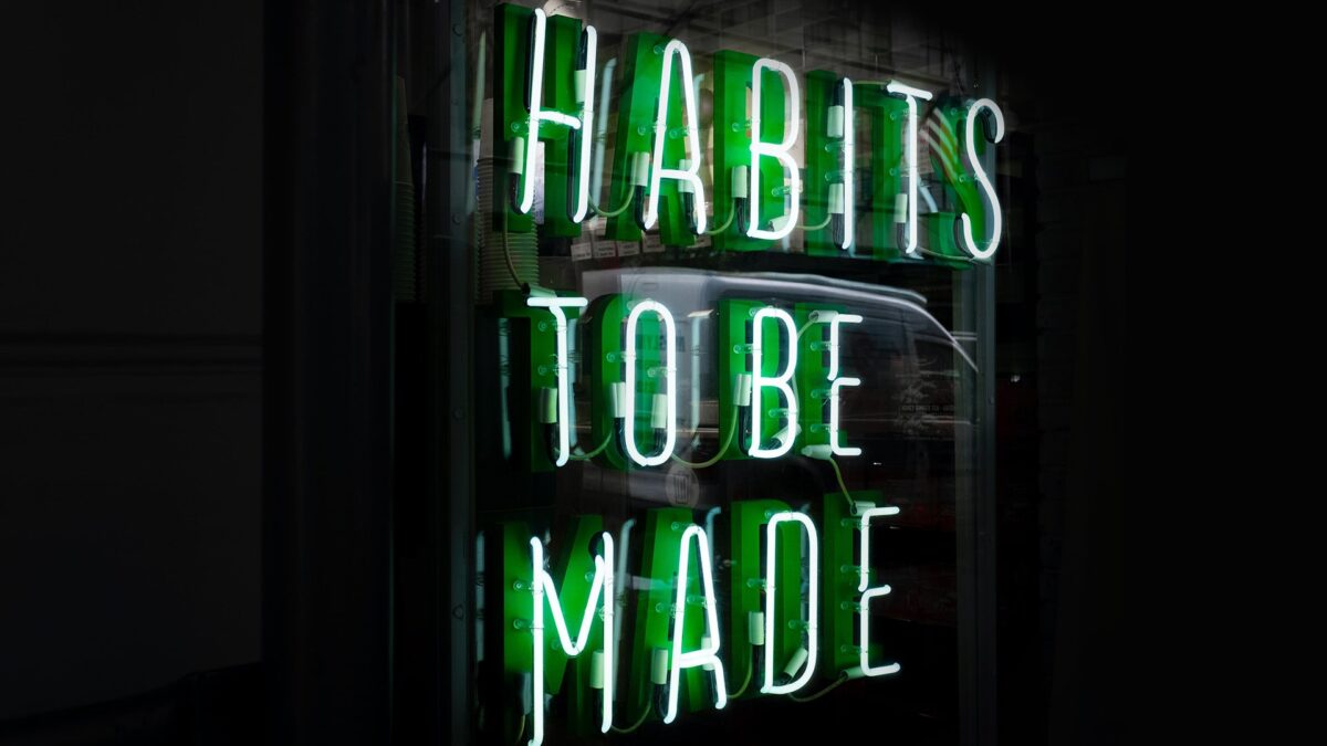Neon green sign reading Habits To Be Made